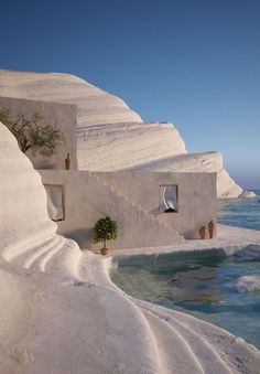 a house built into the side of a cliff by the ocean with snow on it