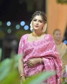 a woman in a pink sari and gold jewelry