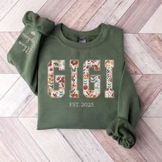 a green sweatshirt with the number six on it and flowers in front of it, sitting on a wooden floor