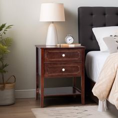 a bedroom with a bed, night stand and lamp on the nightstand next to it