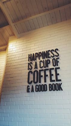 a sign that says happiness is a cup of coffee and a good book on the wall