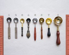 an assortment of spoons and ladles are arranged in a row on a ruler