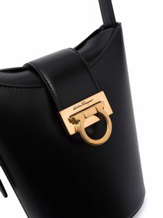 Trifolio bucket bag from SALVATORE FERRAGAMO featuring black, calf leather, engraved logo, gold-tone hardware, buckle fastening, foldover top and adjustable shoulder strap. Size Info UNI Color Detail Black Made In Italy Material Calf Leather 100% Season One Fall-Winter Season Two Fall-Winter Product bags.. Brand Ferragamo Size And Fit Width 11,81 in / 30 cm Height 7,48 in / 19 cm Depth 3,94 in / 10 cm Handle 11,81 in / 30 cm Leather Engraved, Black Bucket Bag, Ferragamo Bag, Salvatore Ferragamo Bags, Leather Engraving, Black Bucket, Crossbody Tote Bag, Moon Boots, Leather Bucket Bag