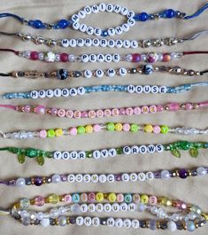 several bracelets are arranged in rows on a bed spread with beads and letters that spell out words