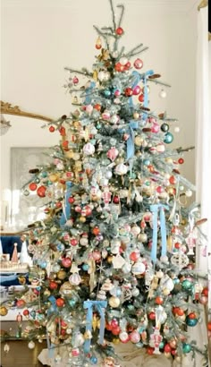 a decorated christmas tree in a living room with blue ribbon and ornaments on the top