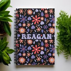 a notebook with the word reagan written on it next to plants and potted plant