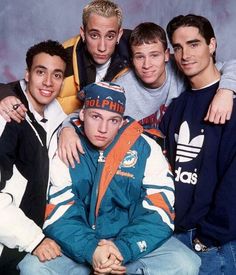 four young men posing for a photo in front of a blue background with one man wearing an adidas jacket