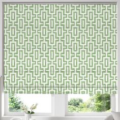 a green roman blind in front of a window with an abstract pattern on it,