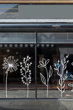 the window is decorated with white flowers and leaves on it's glass front door