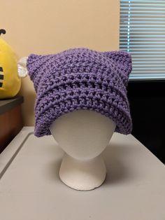 Handmade cat ear beanie made with purple yarn Warm Cat Ears Hat, One Size Fits Most, Warm Cat Ears Hat One Size, Warm Cat Ears Hat One Size Fits Most, Winter Yarn Hats With Cat Ears, Knitted Beanie With Cat Ears, Purple Yarn Crochet Hat For Winter, Adjustable Purple Crochet Hat For Winter, Winter Purple Crochet Yarn Hat, Handmade Cat Ears Hat