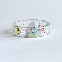 Custom wish Care Bear ring Please make sure to size your finger I will no longer be accepting exchanges as I have to pay for the shipping to send the new size.  Thank you ♥️ & I hope you understand  This adorable ring is so unique.  I made this ring for a customer and she was in love with this item.  So I decided to post it as a listing.  I can't wait to make yours! This ring is unique so no two are the same. The smaller the ring size you may only see half of the belly design Shipping says 5-7 days however most of the time I get the order out within a few days. Colors may be a little lighters however I have and am working on adding non edited photos and videos to all care Bear listings. Very dainty and unique Cute Hypoallergenic Clear Jewelry, Cute Plastic Jewelry For Gifts, Playful Plastic Jewelry For Gifts, Playful Plastic Jewelry As Gift, Playful Plastic Jewelry Gift, Cute Hypoallergenic Plastic Jewelry, Fun Clear Jewelry As Gift, Fun Clear Jewelry For Gifts, Fun Clear Jewelry As A Gift