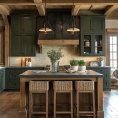 a large kitchen with green cabinets and wooden flooring on the walls, along with two wicker bar stools