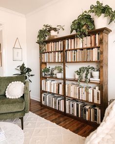 a living room filled with lots of books and plants on top of wooden shelving units