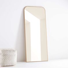 a mirror sitting on top of a white counter next to a small round ottoman in front of it