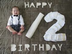 a baby is sitting on the floor next to his first birthday cake and two diapers