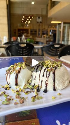 a white plate topped with ice cream covered in chocolate and pistachio toppings