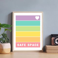 a framed poster with the words safe space on it next to a potted plant