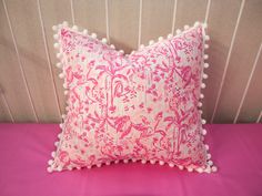 a pink and white pillow with pom - poms on the back of it