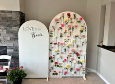 two white archs with flowers on them in front of a fireplace