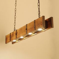 a wooden light fixture with four lights hanging from it's sides and chains on the ceiling