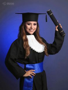 a woman wearing a graduation cap and gown holding a diploma in one hand while smiling at the camera