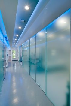 an empty hallway with frosted glass walls and blue lighting