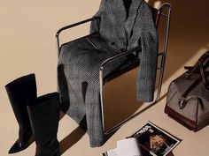 a woman's purse and boots sitting on top of a chair next to an open magazine