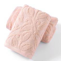 two light pink towels folded on top of each other, one with an intricate design