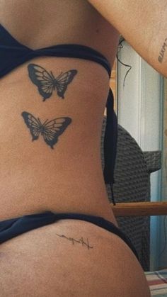 a woman's stomach with two butterfly tattoos on her lower back and upper side