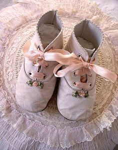 pair of baby shoes with bows on lace doily