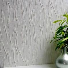 a plant in a silver vase sitting on a white shelf next to a gray wall