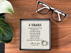 a wooden table topped with glasses next to a plant and eyeglasses on top of it