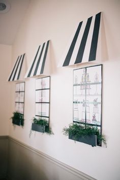 three windows with black and white striped awnings on the side of a wall