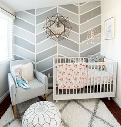 a baby's room decorated in gray and white with a chevron wallpaper