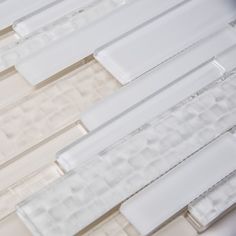 several white and clear glass tiles are arranged in the same pattern, with one light shining on them