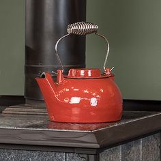 a red tea kettle sitting on top of a stove