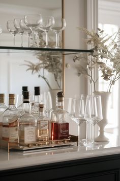 bottles and glasses are sitting on a bar with a mirror in the backround