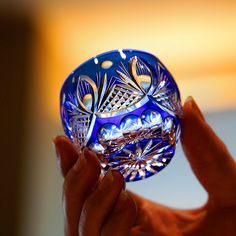 a person holding a blue glass bowl in their hand with the light shining on it