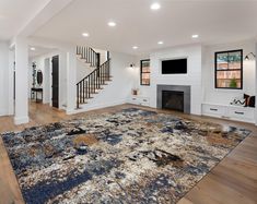 a living room with white walls and wooden floors, an area rug on the floor