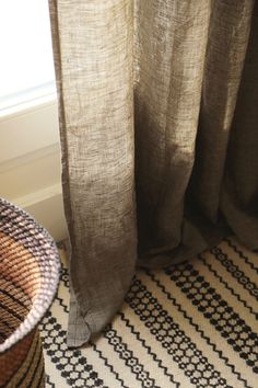 a close up of a rug with a window in the back ground and a basket on the floor next to it