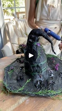 a woman is using a hair dryer to decorate a witches hat on top of a table