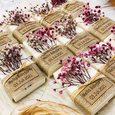 some flowers that are sitting on top of a white table cloth with tags attached to them