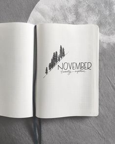 an open book with the words november written in black on it and pine trees behind it