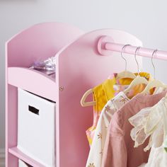 a pink toy chest with clothes hanging on it