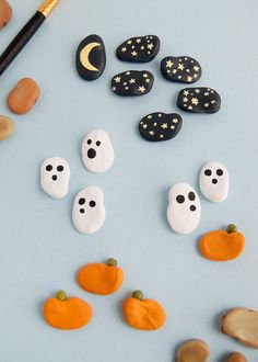 halloween decorations made out of rocks on a blue surface with a paintbrush next to them