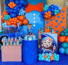 there is a blue and orange party set up with balloons, streamers and decorations