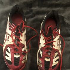 a pair of red and white shoes with laces on the bottom, sitting on a black surface