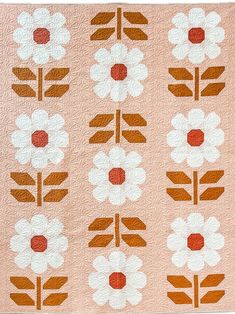 an orange and white quilt with flowers on it