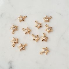 Star charms/pendants, 18K gold plated brass with clear cubic zirconia Size: Approx 10.5 X 9mm Holes: Approx 1.2mm Quantity: 2 pcs in a pack Gold Star-shaped Jewelry With Sparkling Stones, Gold Star Jewelry With Sparkling Stones, Gold Star, Star Charms, Jewellery Making, Gold Stars, Cubic Zirconia, 18k Gold, Gold Plate