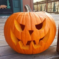 a carved pumpkin sitting on top of a wooden porch